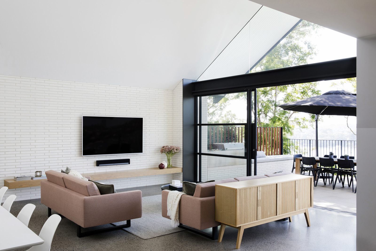 A living room with an exposed white brick interior with adjacent outdoor entertainment area.