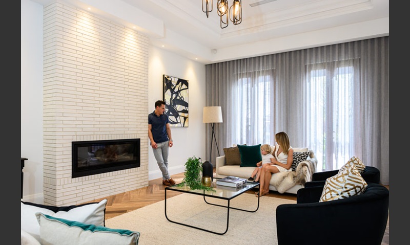 Designer decorated indoor space with a couple talking by a white brick fireplace.