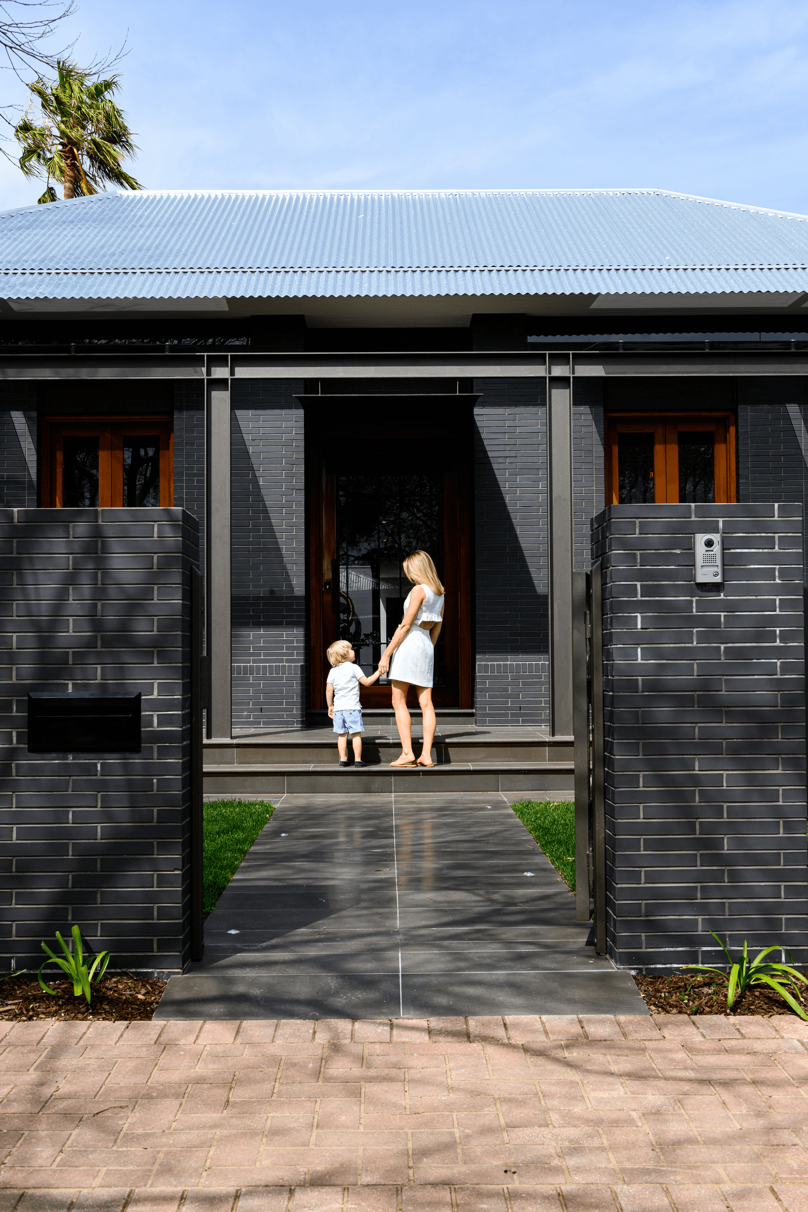 Front of home with mother and child along dark bricks using PGH bricks.