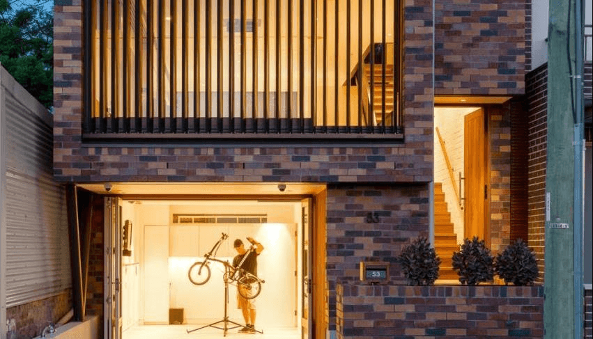 Textural brick used in residential home with man servicing bicycle in garage.